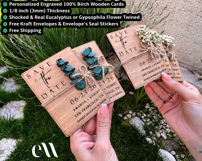 May include: Two wooden save the date cards with the text "Save the Date" and the date "06-23-26" printed on them. The cards are decorated with sprigs of eucalyptus and twine. The cards are held in the hands of a person.