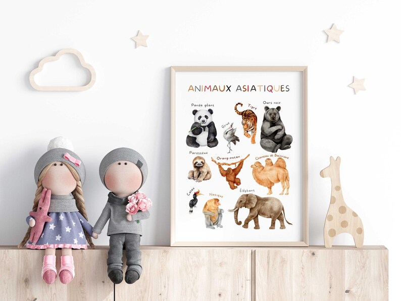 May include: A framed print titled "ANIMAUX ASIATIQUES" featuring watercolor illustrations of Asian animals, including a panda, tiger, and elephant. The print is displayed with two dolls and wooden decorations.