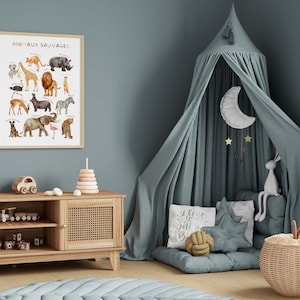 May include: A framed poster with the text "ANIMAUX SAUVAGES" displays watercolor illustrations of various animals. A wooden cabinet holds toys, and a canopy bed with a moon and stars hangs in the corner. The room is decorated in shades of blue and beige.