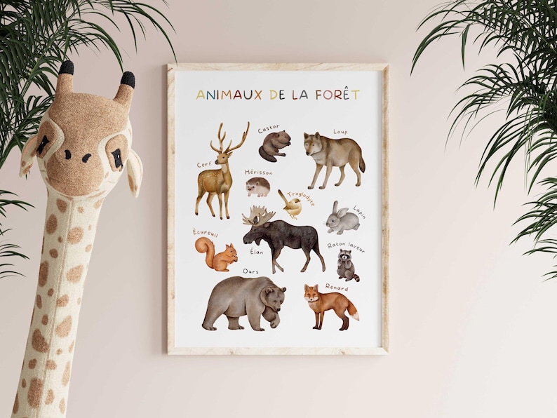 May include: A framed print featuring watercolor illustrations of forest animals, including a deer, bear, and fox. The title "ANIMAUX DE LA FOR&Ecirc;T" is displayed in colorful letters at the top. A giraffe head toy is in the foreground.