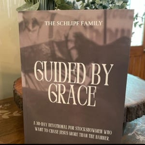 May include: A book titled "GUIDED BY GRACE" with the text "THE SCHLIPF FAMILY" at the top. The book is a 30-day devotional for stock showmen. The cover is a dark gray color with white text.
