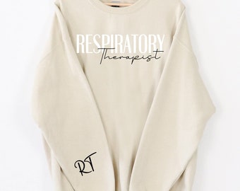 May include: A beige sweatshirt with the text "RESPIRATORY Therapist" in black and white on the front and "RT" in black on the left sleeve.