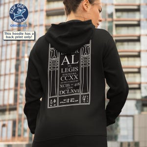 Puede incluir: Sudadera con capucha negra con un gr&aacute;fico blanco en la espalda. El gr&aacute;fico incluye el texto "AL VEL LEGIS SUB FIGVRA CCXX AS DELIVERED BY XCIII = 418 VINTO DCLXVI". La sudadera tiene capucha y mangas largas.
