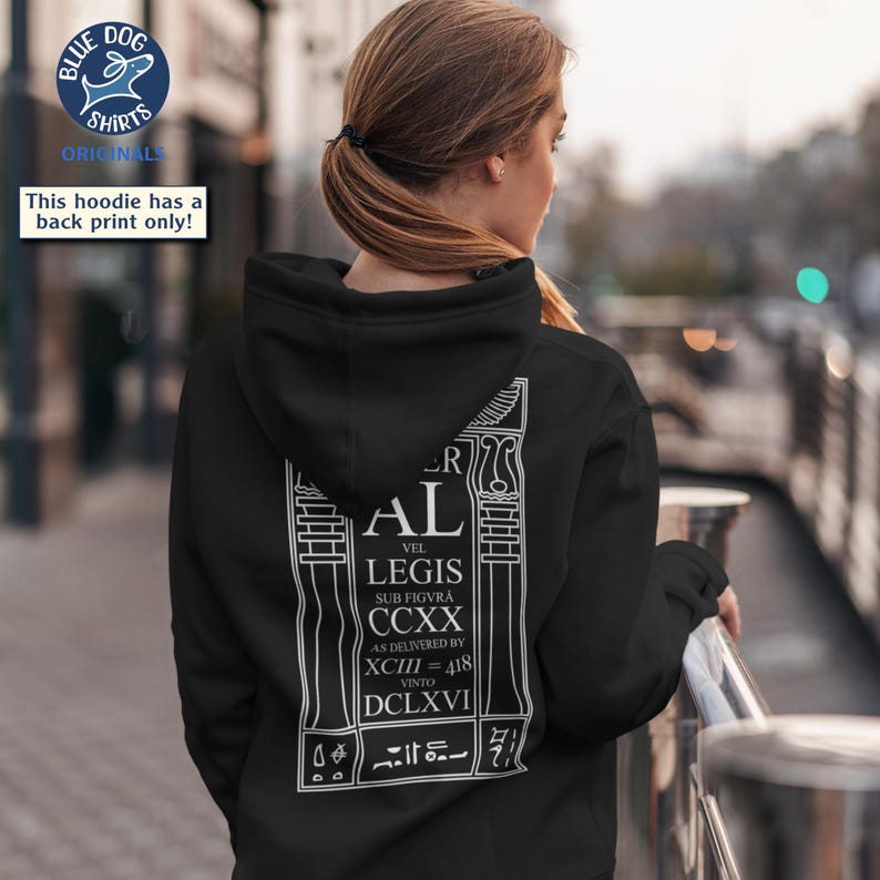 Puede incluir: Sudadera con capucha negra con un estampado gr&aacute;fico blanco en la espalda. El estampado incluye el texto "AL VEL LEGIS SUB FIGVRA CCXX AS DELIVERED BY XCIII=418 VINTO DCLXVI". La sudadera tambi&eacute;n tiene capucha y bolsillo canguro.