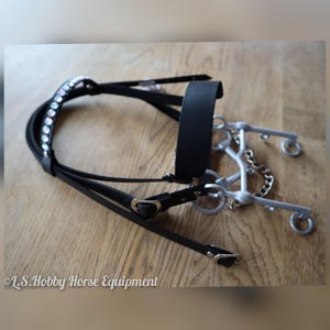 K&ouml;nnte beinhalten: Schwarzes Leder-Pferdehalfter mit silbernem Gebiss und einer Reihe von regenbogenfarbenen Strasssteinen auf dem Stirnband. &copy; L.S. Hobby Horse Equipment