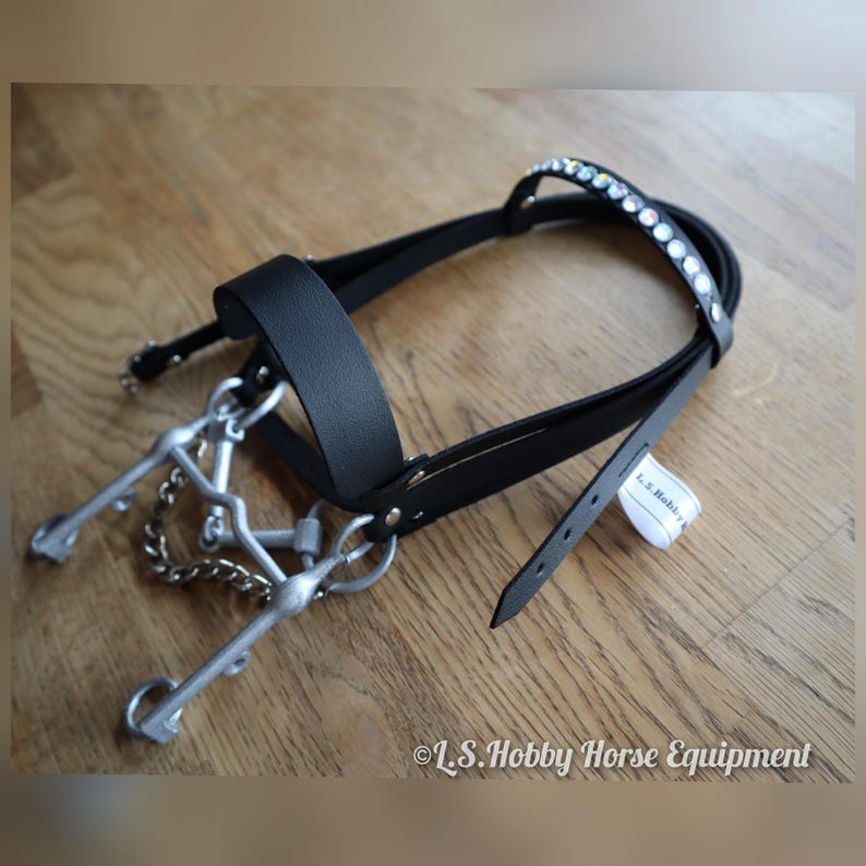 K&ouml;nnte beinhalten: Schwarzes Leder-Hobbypferde-Zaumzeug mit silbernem Gebiss und einer Reihe von klaren Strasssteinen auf dem Stirnriemen. Das Zaumzeug hat ein Etikett mit der Aufschrift "L.S. Hobby".