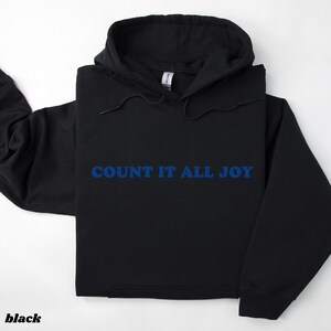 May include: Black hoodie with the blue text "COUNT IT ALL JOY". The hoodie has a drawstring hood and a front pocket. The word "black" is printed at the bottom left corner of the image.
