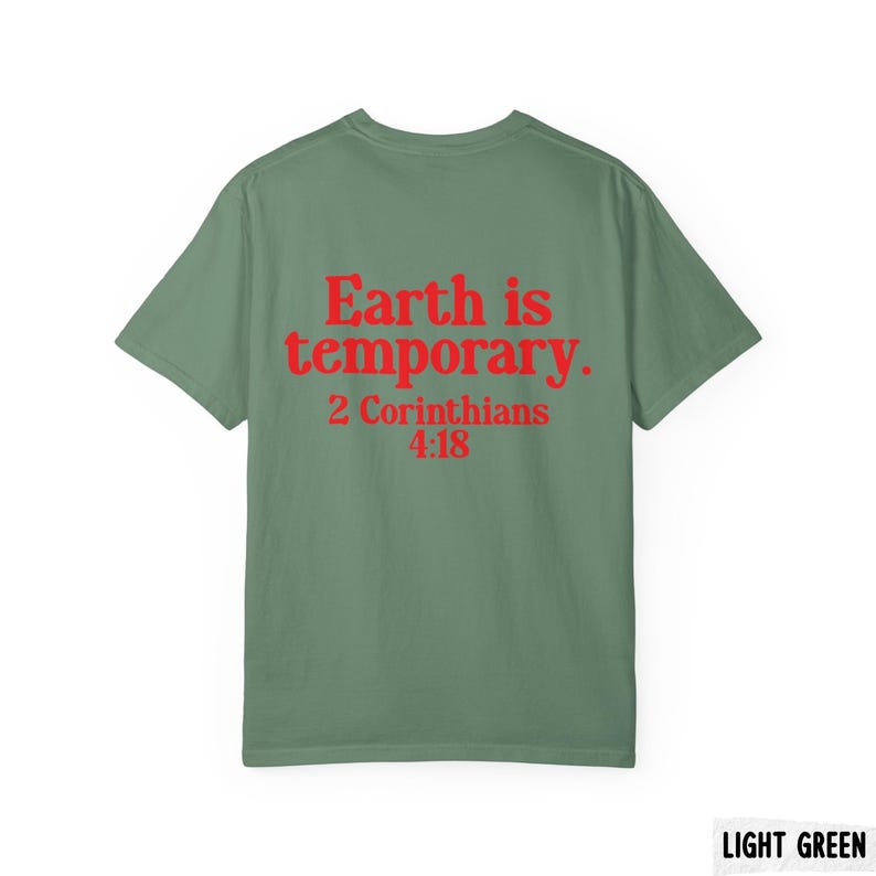Pode incluir: T-shirt verde claro com o texto vermelho "Earth is temporary. 2 Cor&iacute;ntios 4:18". A t-shirt &eacute; de cor lisa e tem um design cl&aacute;ssico de gola redonda. O texto est&aacute; centrado nas costas da t-shirt.