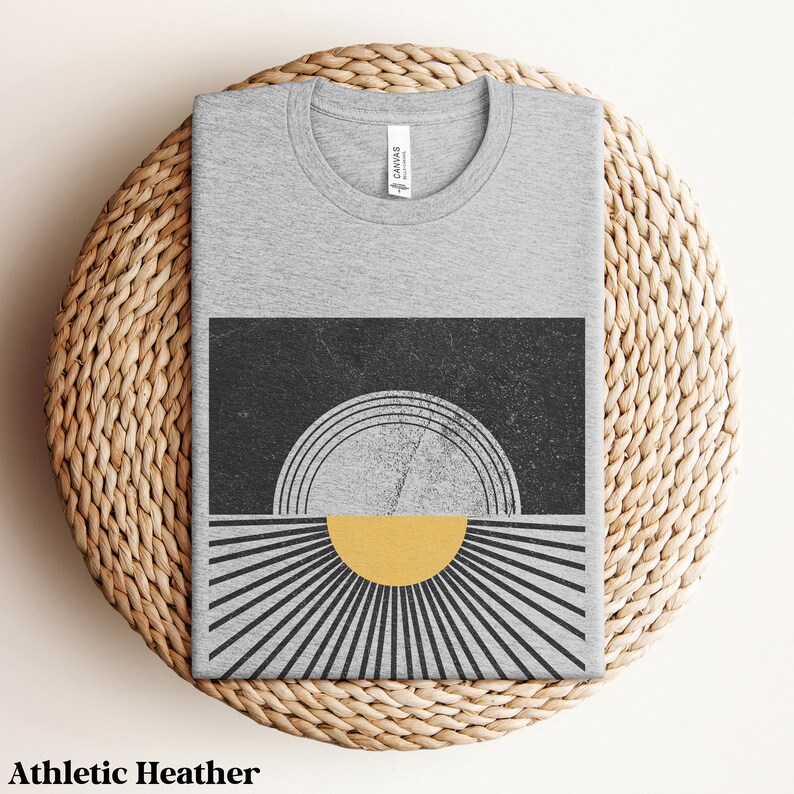 May include: A gray t-shirt with a black and yellow graphic design of a sun with rays. The design has a distressed look.