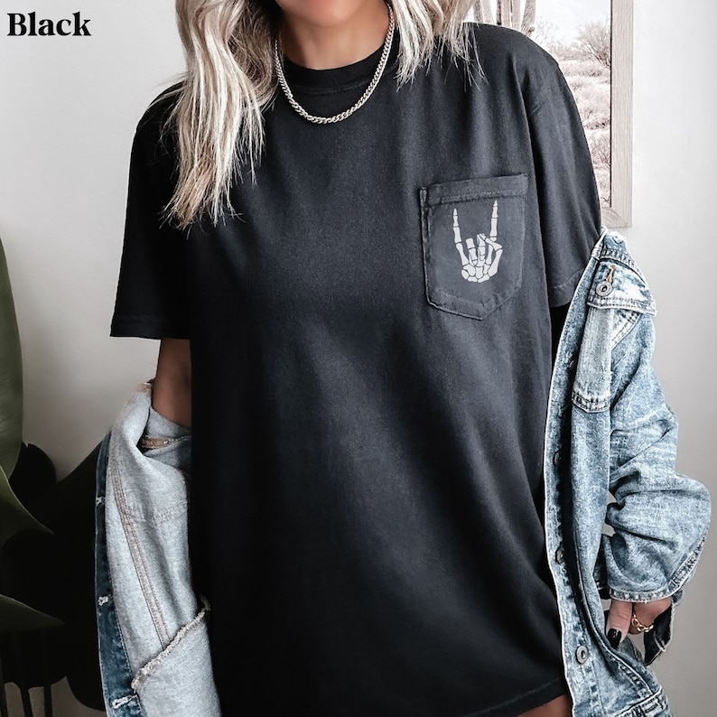 May include: Black t-shirt with a skeleton hand graphic in the pocket. The t-shirt is made of a soft, comfortable material and has a relaxed fit.