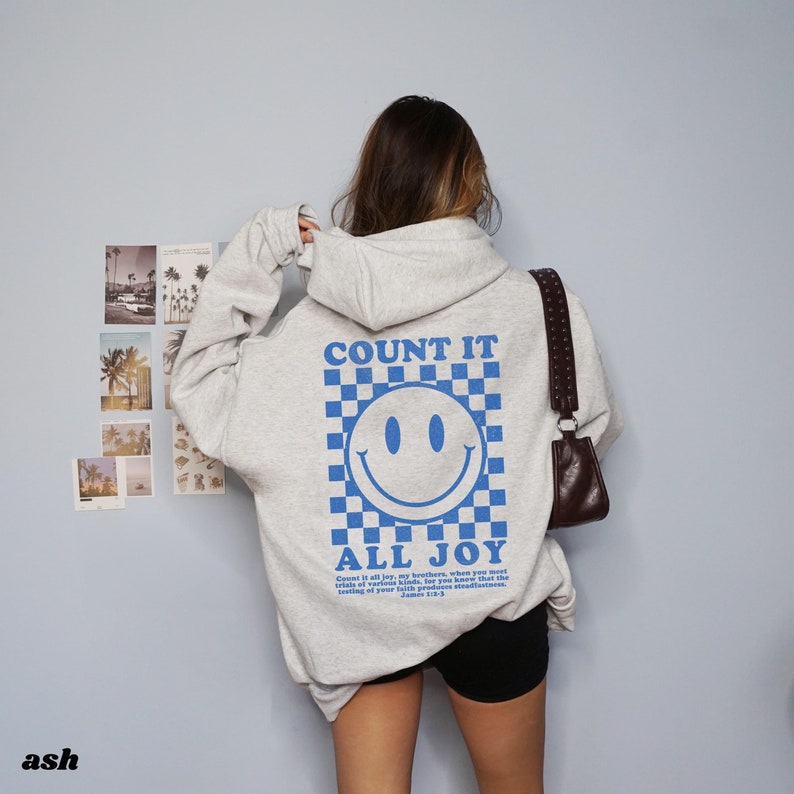 May include: A light grey hoodie with a blue smiley face graphic and the text "COUNT IT ALL JOY" on the back. The text below the smiley face reads "Count it all joy, my brothers, when you meet trials of various kinds, for you know that the testing of your faith produces steadfastness." James 1:2-3