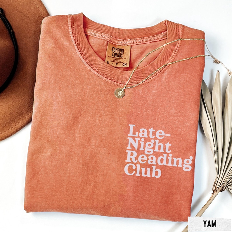Puede incluir: Una camiseta naranja quemada con el texto "Late-Night Reading Club" impreso en blanco.