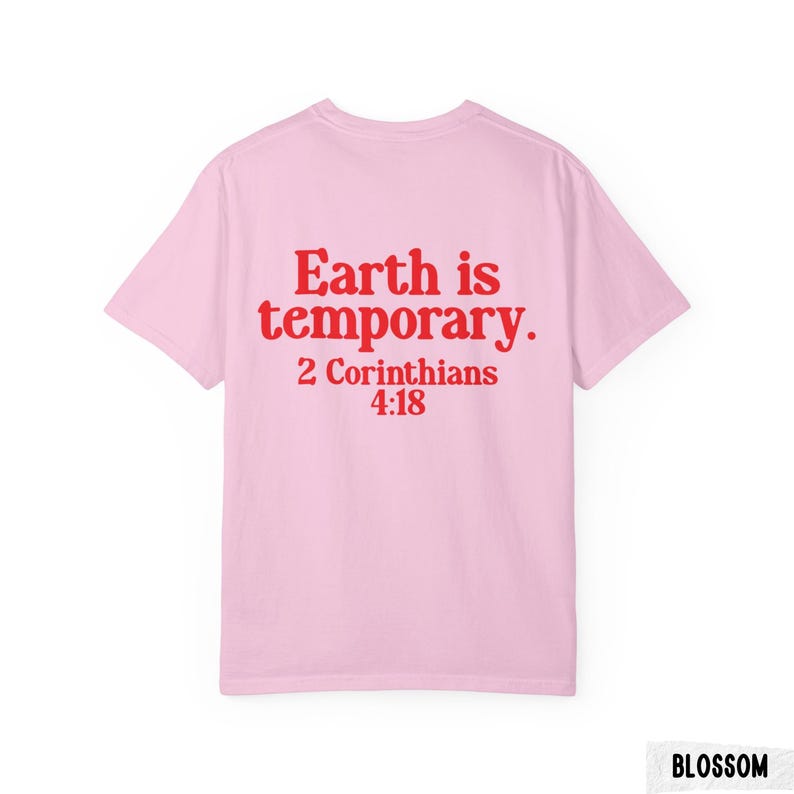 Pode incluir: T-shirt rosa claro com a frase vermelha "Earth is temporary. 2 Cor&iacute;ntios 4:18" nas costas. A t-shirt tem um estilo de gola redonda.