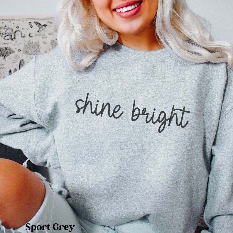 May include: A gray sweatshirt with the text "shine bright" in black script.