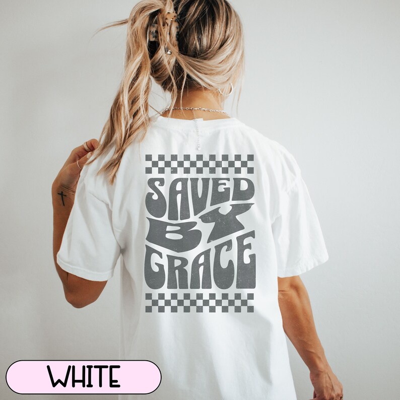 May include: White t-shirt with a checkered pattern and the text "SAVED BY GRACE" in a retro font.