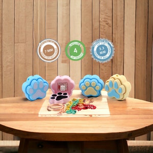 May include: Four colorful paw print keychains with a light blue, pink, yellow, and light blue color scheme. The keychains are compatible with up to 7 mm diameter keychains. The keychains are also compatible with up to 3.3 mm diameter ball chains. The keychains are made of silicone and have a paw print design. The keychains are a unique and fun way to add a touch of personality to your keys.