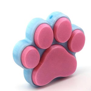 May include: A light blue paw-shaped fidget toy with five pink dimples. The toy is made of a soft, squishy material.