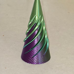 May include: A green and purple 3D printed cone with a spiral design.