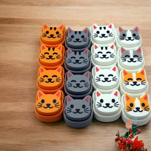 Può includere: Un set di 12 puntine da disegno in ceramica a forma di gatto in vari colori, tra cui arancione, grigio e bianco. Le puntine presentano diverse espressioni facciali e sono perfette per aggiungere un tocco giocoso a qualsiasi bacheca o pannello di sughero.