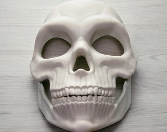 May include: White plastic skull mask with eye holes and a toothy grin.
