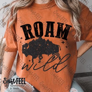 May include: A burnt orange t-shirt with a black graphic design featuring a buffalo silhouette, mountains, and the text "ROAM wild".