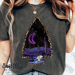 May include: A purple crescent moon glows in a dark sky above a desert landscape with tall cacti and a skull with horns. The scene is framed by a leopard print border.