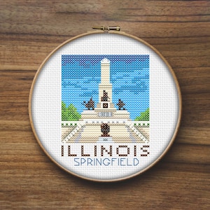 May include: A cross-stitch embroidery hoop with a colorful image of the Lincoln Monument in Springfield, Illinois. The text "ILLINOIS SPRINGFIELD" is below the image.