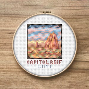 Pode incluir: Padrão de ponto cruz de uma cena de paisagem com uma formação rochosa vermelha em primeiro plano, um céu azul com nuvens e o texto "CAPITOL REEF UTAH".