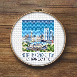 May include: Cross-stitch pattern of the Charlotte skyline, including the Bank of America Stadium, with the text "North Carolina Charlotte" below.