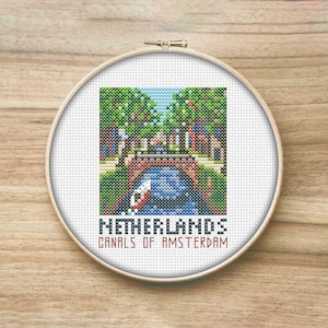 May include: A cross-stitch embroidery design of a canal in Amsterdam, Netherlands. The design features a bridge, a boat, and trees. The text "Netherlands Canals of Amsterdam" is below the image.