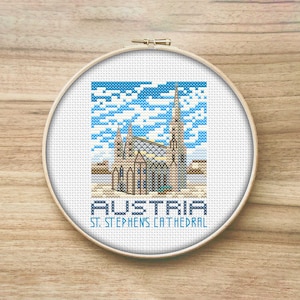 May include: A cross-stitch pattern of St. Stephen's Cathedral in Vienna, Austria. The pattern is in a white hoop with a blue sky and white clouds. The text "Austria St. Stephen's Cathedral" is below the image.