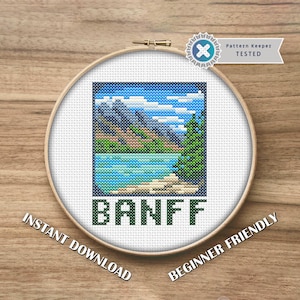 May include: A cross-stitch embroidery hoop featuring a landscape scene of Banff, with mountains, a lake, and a pine tree. The word "BANFF" is stitched in green block letters. The text "INSTANT DOWNLOAD" and "BEGINNER FRIENDLY" are also included.
