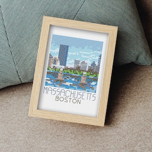 May include: A framed cross-stitch artwork depicting a cityscape with the text "MASSACHUSETTS BOSTON" at the bottom.