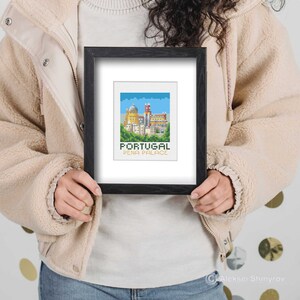 May include: A framed cross-stitch design featuring a colorful depiction of Pena Palace in Portugal. The text "PORTUGAL PENA PALACE" is below the image.