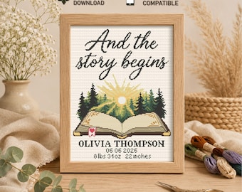 May include: A framed cross-stitch piece with the text "And the story begins." Below the text is an open book with a forest and sun design. The name "OLIVIA THOMPSON" and birth details are below the book. The frame is wood, and the piece is 22 inches long.