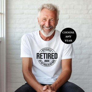 May include: White t-shirt with a black circle graphic that says "Officially Retired 2024 Not My Problem Anymore".