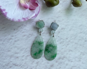 May include: A pair of jade earrings with a carved flower design. The earrings are green and white with silver accents.