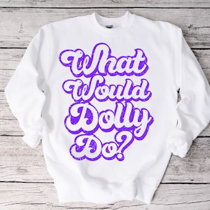 Pode incluir: Camisola branca com texto roxo que diz "What Would Dolly Do?" em uma fonte retrô.