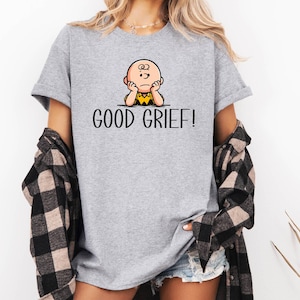 May include: A grey t-shirt featuring a cartoon image of Charlie Brown with the text "GOOD GRIEF!" printed on it.