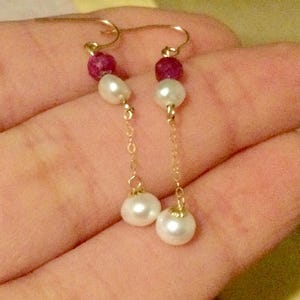 Peut inclure: Une paire de boucles d'oreilles pendantes avec des crochets dorés, chacune ornée d'une petite perle magenta texturée, d'une perle d'eau douce blanche, d'une fine chaîne dorée et d'une perle d'eau douce blanche plus grande à l'extrémité.