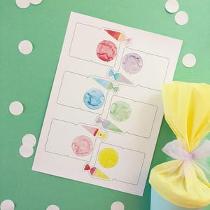Könnte beinhalten: Ein Blatt Papier mit Aquarellillustrationen von bunten Süßigkeiten und Kreisen, mit einem hellblauen kegelförmigen Behälter, der einen gelben, mit Tüll umwickelten Gegenstand enthält. Weiße Konfettipunkte auf dem grünen Hintergrund.