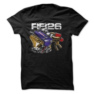 May include: Black t-shirt featuring a detailed illustration of an engine with gold, blue, and red components. The text "RB26" is printed in white above the engine graphic, with a distressed, grunge-style font.