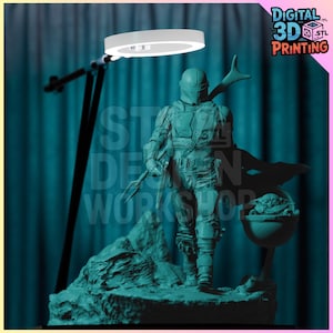 Puede incluir: Una figura impresa en 3D de color verde azulado de un personaje de la franquicia Star Wars, The Mandalorian, sosteniendo un arma y de pie sobre una base rocosa. El personaje lleva un casco y una armadura. La figura está iluminada desde arriba por una luz de anillo.