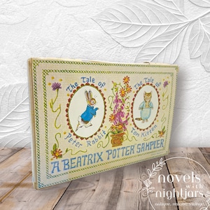May include: A vintage sampler featuring illustrations of Peter Rabbit and Tom Kitten. The sampler has a cream-colored background with embroidered details, including floral accents and the text "A Beatrix Potter Sampler."
