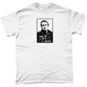Może przedstawiać: Biały t-shirt z czarno-białym obrazkiem twarzy mężczyzny w stylu zdjęcia policyjnego. Pod obrazkiem nadrukowany jest tekst "FASHION IS A CRIME".