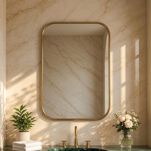 Puede incluir: Un espejo de pared rectangular con esquinas redondeadas y un marco dorado fino. El espejo está montado sobre una encimera de mármol verde oscuro con un lavabo circular, un grifo dorado y dos manijas doradas, junto a una planta y flores.