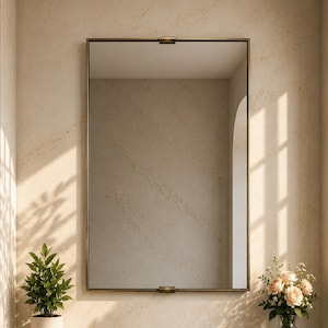May include: A rectangular wall mirror with a thin bronze frame, positioned above a dark green marble vanity countertop featuring a circular sink basin, three brass faucet handles, a stack of white towels, a potted plant, and a glass vase of roses.