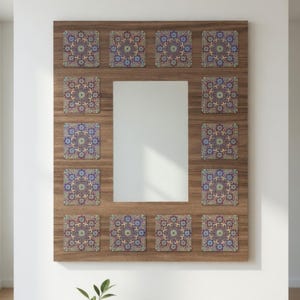 Könnte beinhalten: Rechteckiger Spiegel mit Holzrahmen und zentraler Spiegelfläche. Der Rahmen ist mit dekorativen quadratischen Fliesen mit einem sich wiederholenden Blumenmuster in Blau, Lila und Beige verziert. Der Spiegel ist an einer weißen Wand befestigt. Maße: 75 cm x 100 cm.