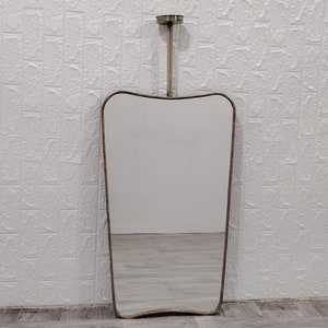 May include: A tall, silver-framed mirror with a wavy, asymmetrical shape. The mirror is hanging from a silver rod.