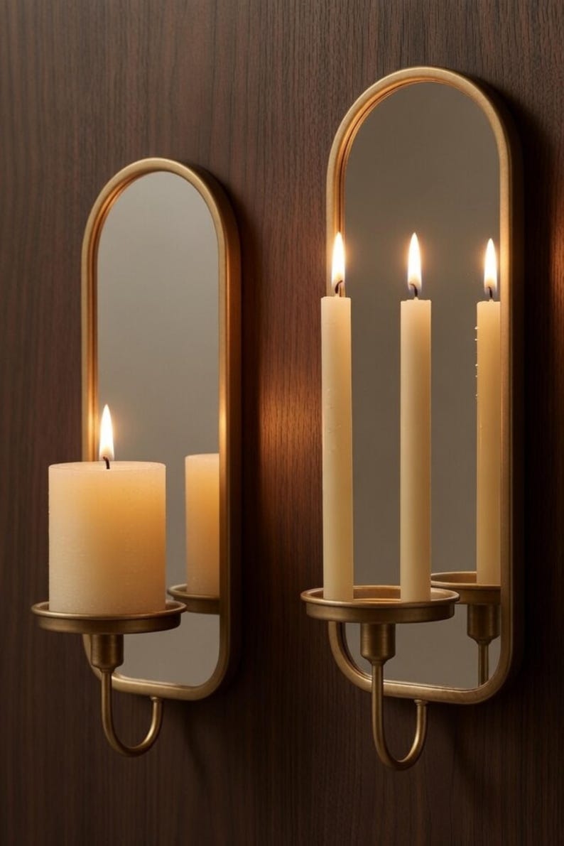 Puede incluir: Dos apliques de pared dorados con espejos y candelabros. Uno sostiene una vela gruesa encendida, el otro tres velas encendidas. Los apliques est&aacute;n montados en una pared de madera marr&oacute;n oscuro, creando un ambiente c&aacute;lido.